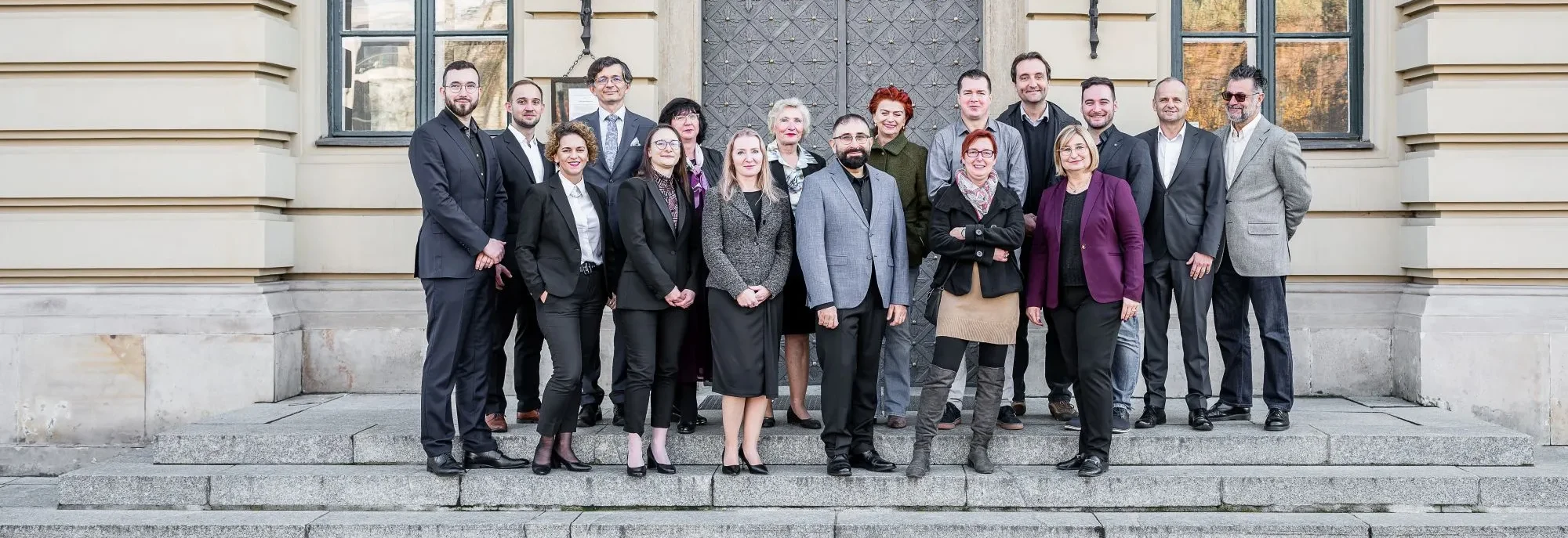 Grupa ludzi na tle drzwi wejściowych do Budynku Głównego UEK