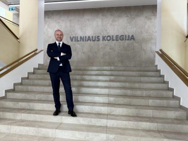 Mężczyzna w garniturze, stoi na schodach w budynku