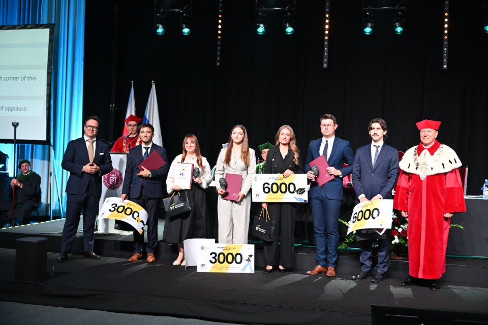 Laureaci konkursu Laury Akademickie stojący w rzędzie z Rektorem trzymają symbole otrzymanych nagród i dyplomy, zdjęcie zrobione w trakcie uroczystej inauguracji